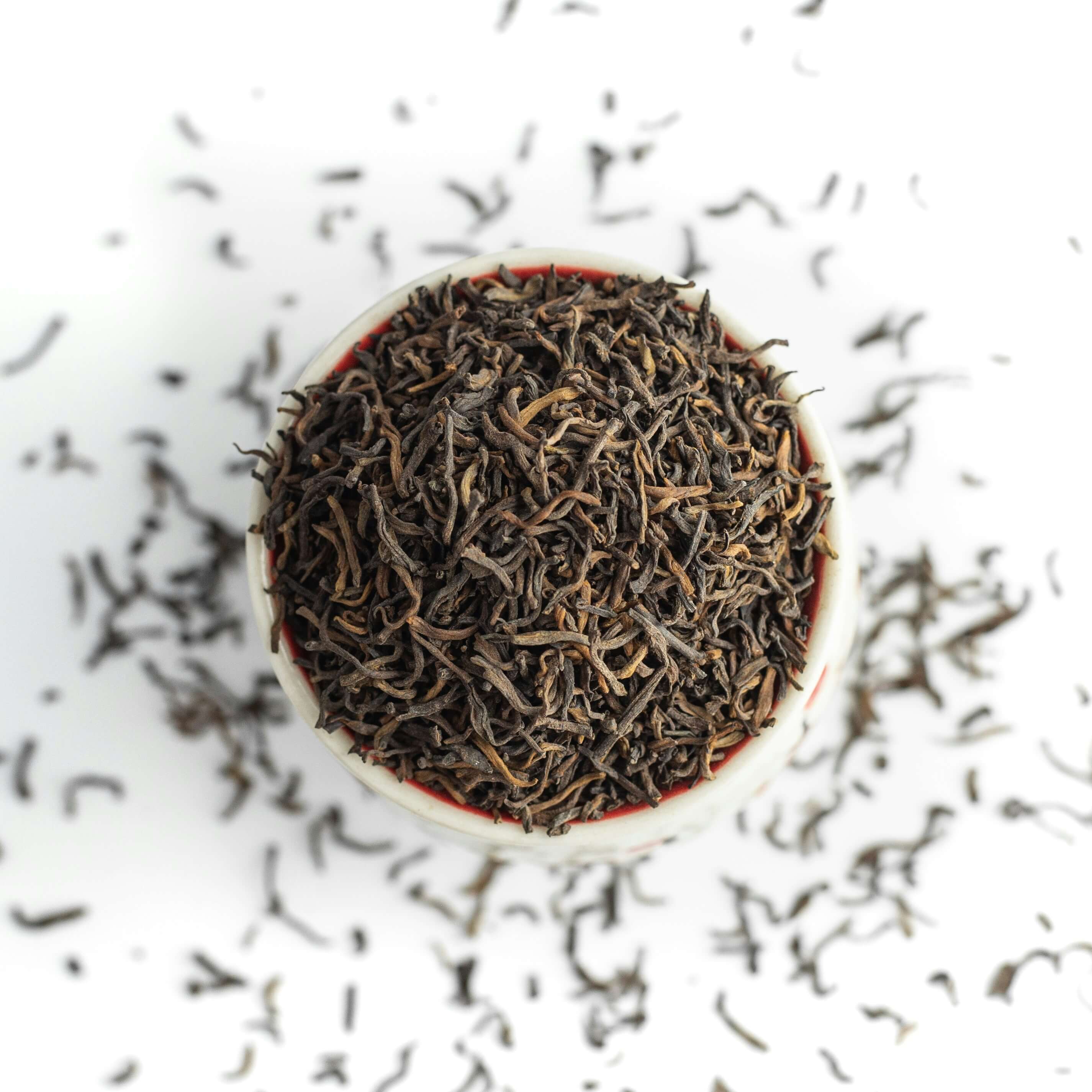 a bowl of loose black tea that is overflowing onto a white surface