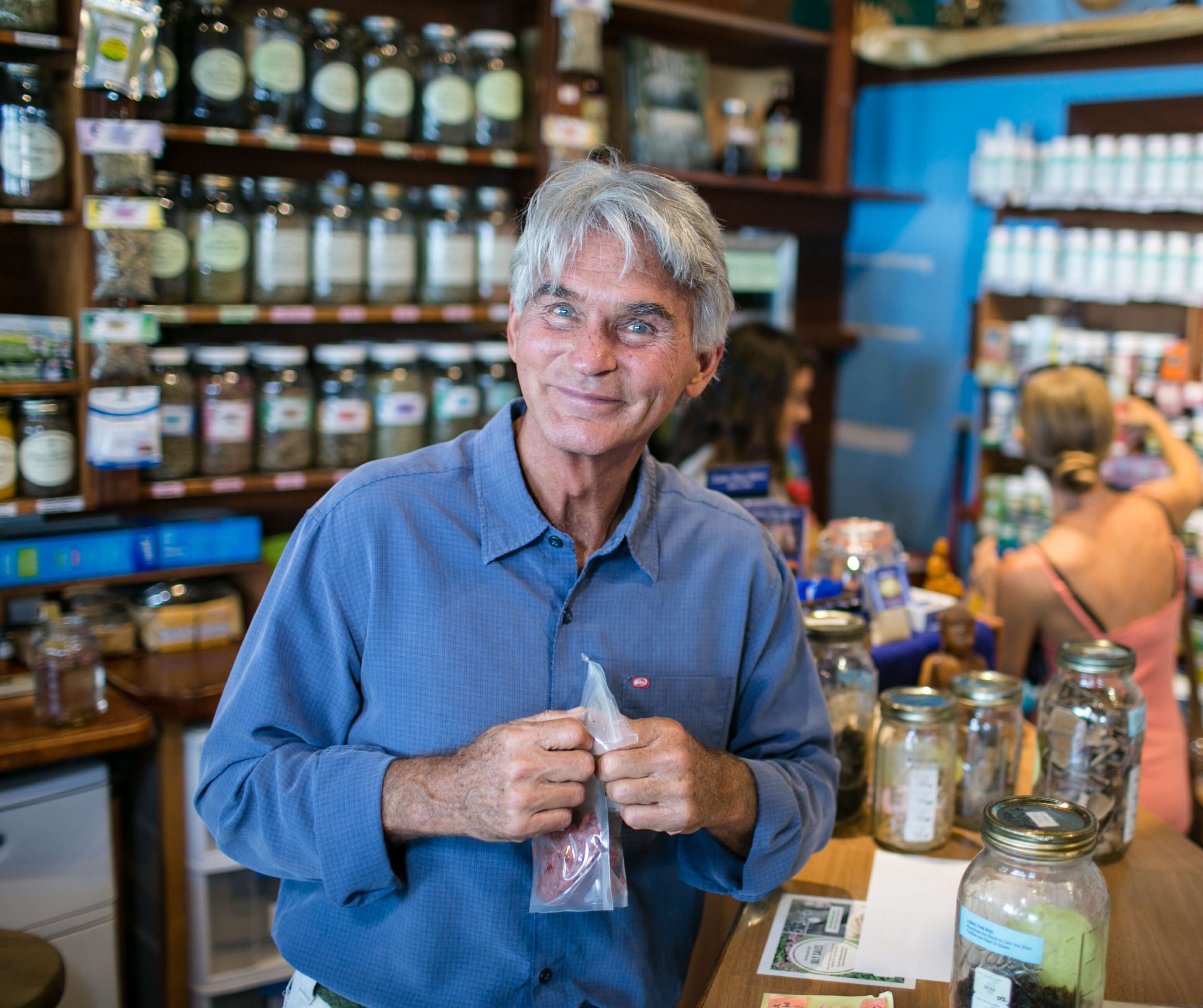 dr. malik cotter standing behind the dragons den counter smiling into the camera